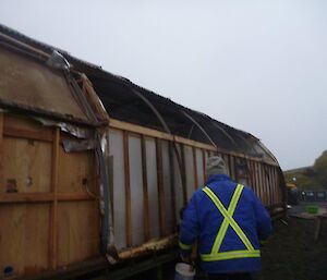 A man in front of the building which now is missing one wall.