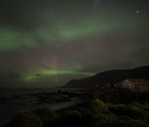 A night shot looking south with the green and red of an aurora in the sky