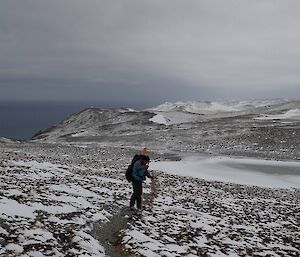 A man hammering in a track marking pole on the snowy plateau