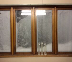 An upstairs window with snow piled up.