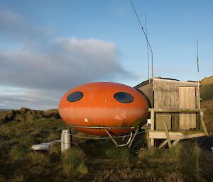 An orange ‘smartie’ shaped hut — this is Waterfall bay hut