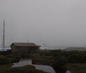 A small wooden building on the coast surrounded by aerials and monitoring equipment