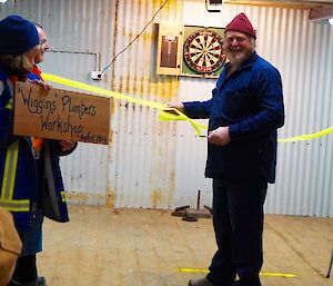 A man is cutting a green ribbon in the shed