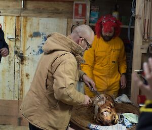 2 men carving a roast pig