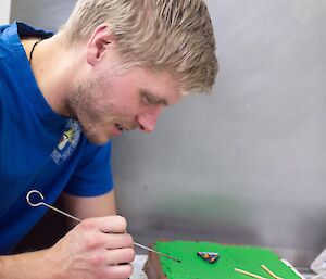 A man is icing a pool table cake