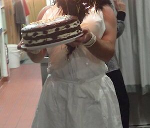 A man dressed as Marilyn Monroe, carrying a birthday cake.