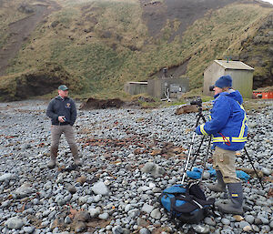 A man being interviewed on the beach with elephant seal in background