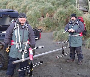 2 men in hiking gear with the antenna slung between them