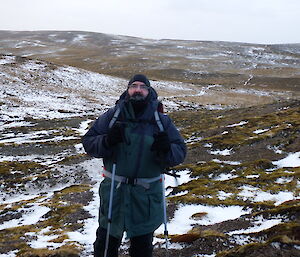 A man looks at camera with snowy landscape behind him