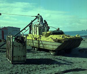 Horse in horsebox on DUKW amphibious vehicle about to be craned out whilst other horsebox sits on the ground nearby