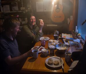 Two expeditioners and scones on table in hut