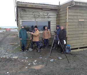 A group of people with filming equipment in front of a building