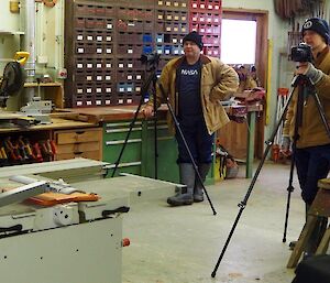 2 men with cameras on tripods in a workshop