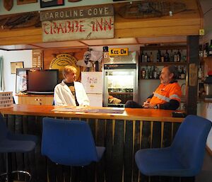 2 men sitting talking at a bar