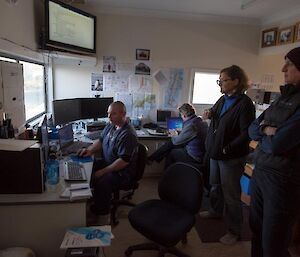 4 people in a room full of monitors.