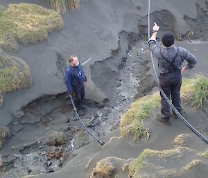 2 men talking in a creek bed — erosion of side walls evident