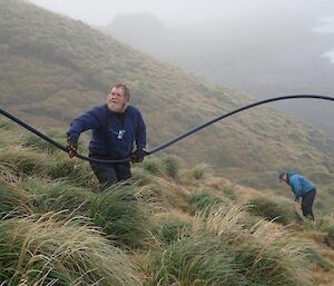 2 men on a steep hillside with a pipe