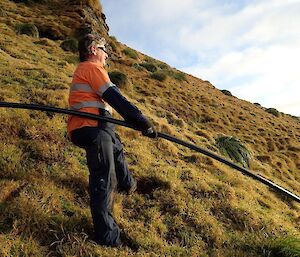 A man on a steep slope with a pipe