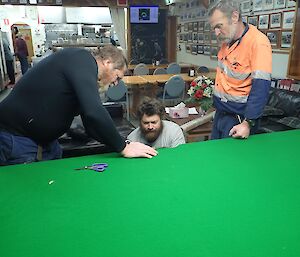 3 men stretching felt over a pool table