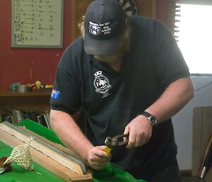 A man working with the wooden sides of the pool table