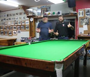 Two men giving the thumbs up over their newly finished pool table
