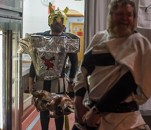 2 men in costume carry in a pig on a spit