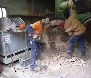 2 men working on the door of an incinerator