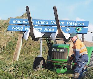 A man with a tractor installing a new sign for the island