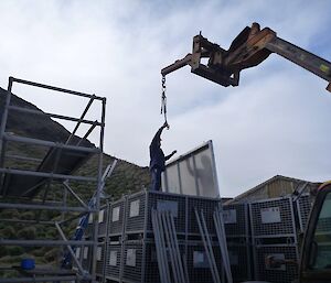 A man guiding the new door on the crane into position