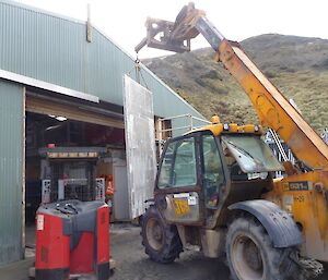 A loader positioning the new door near the Green Store