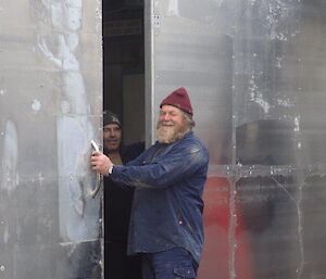 Two men on either side of the new door testing that it works.