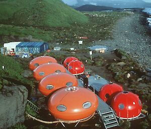 A picture of round, orange ‘Googie’ huts in their original location at Heard Island