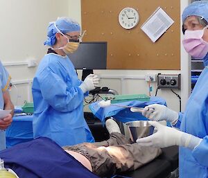 Three people in a room getting ready for a surgical procedure