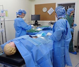 Three people with a dummy patient in an operation exercise