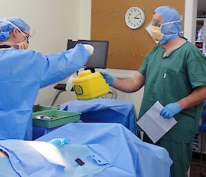 A man and a woman post surgery with a sharps bucket