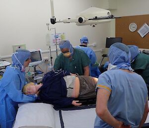 A group of people moving a dummy patient between trolleys