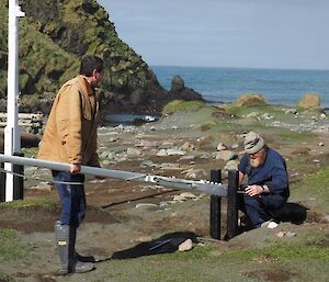 Two men erecting a newly painted flagpole into position