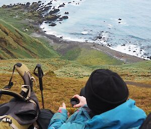 A man having a cup of tea above Hurd Point looking down at the water