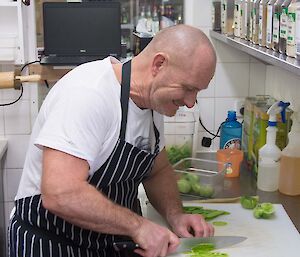 A man chef cuts vegetables in the kitchen in preparation of a feast