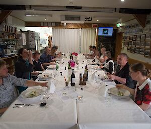 A group of people seated around a large dinner table eating.