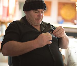 A man trying to remove a puzzle from his shirt