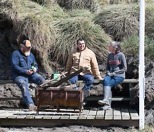 Three people sitting on the newly built deck in the sun