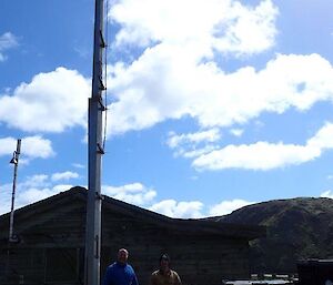 Two men standing with the shiny new Macquarie Island clean air sampling mast