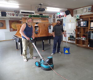 Two men in the mess with a floor polisher