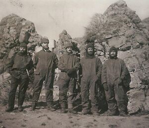 Five men in front of a hut