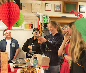 A woman unwraps her present while others watch