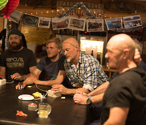 A group of men sit around a quiz table