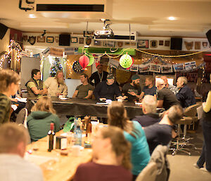 People sit around a table for a quiz game with an audience