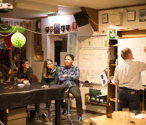 A man draws on a whiteboard as people watch