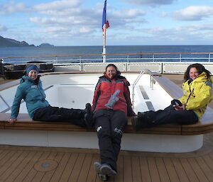 3 women sit on the edge of an empty pool on board